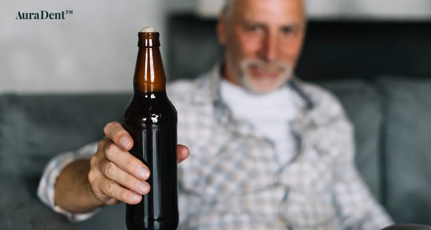 Det här fotot visar en man som håller i ett glas öl (alkohol)